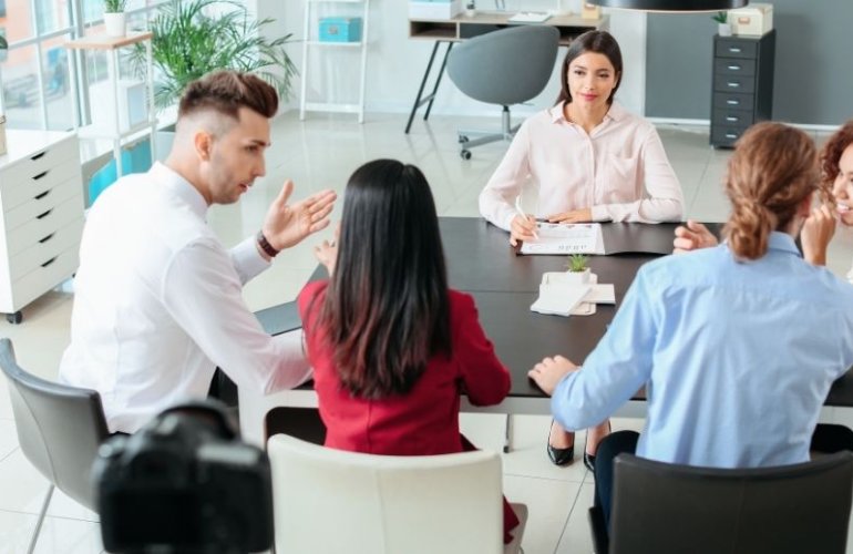 Team diskutiert gemeinsam Aufgaben und zeigt kommunikative Soft Skills im österreichischen Arbeitsalltag